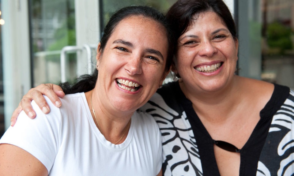 Two mature hispanic women posing together laughing